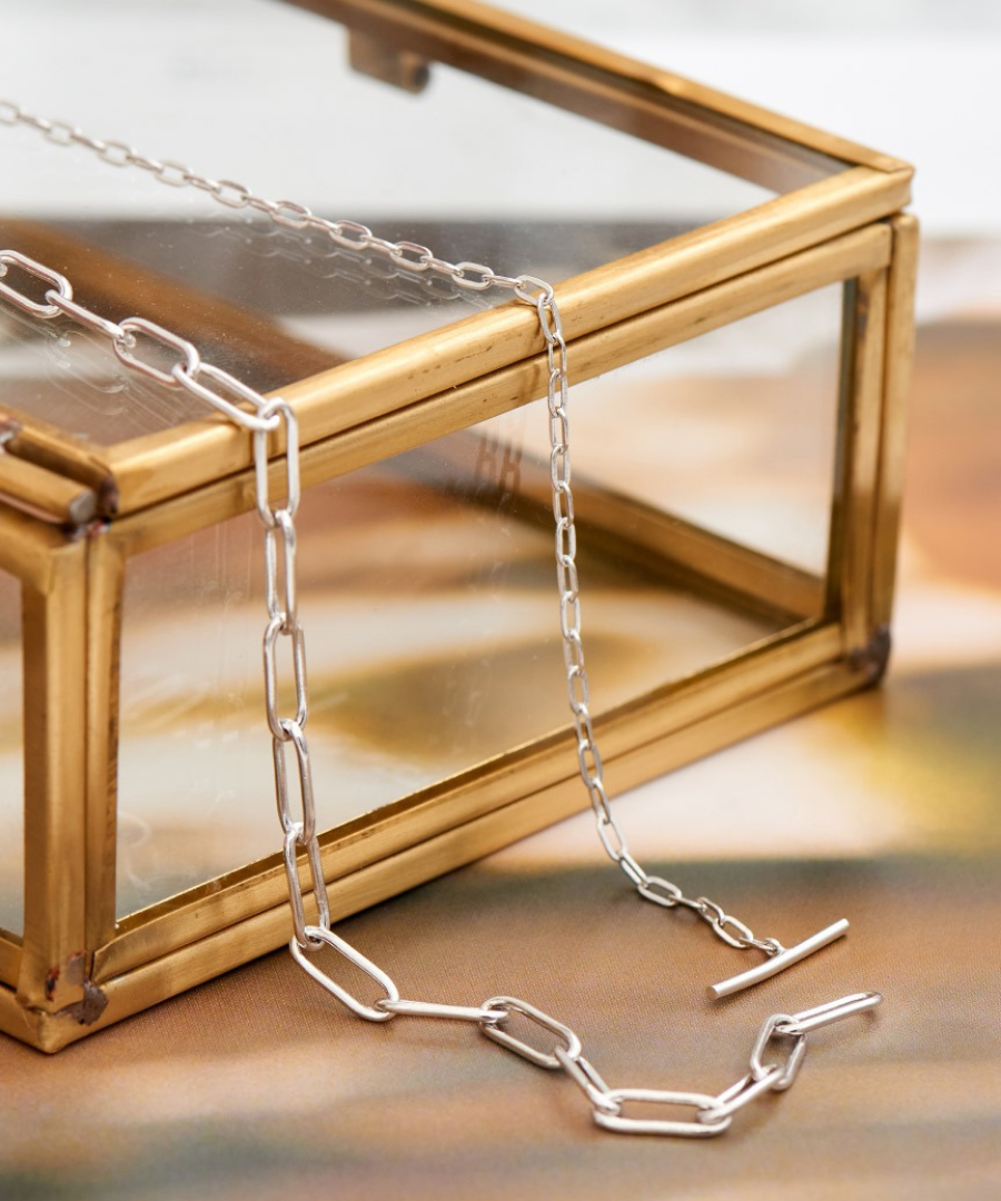 Ania haie chain necklace draped over glass jewellery box