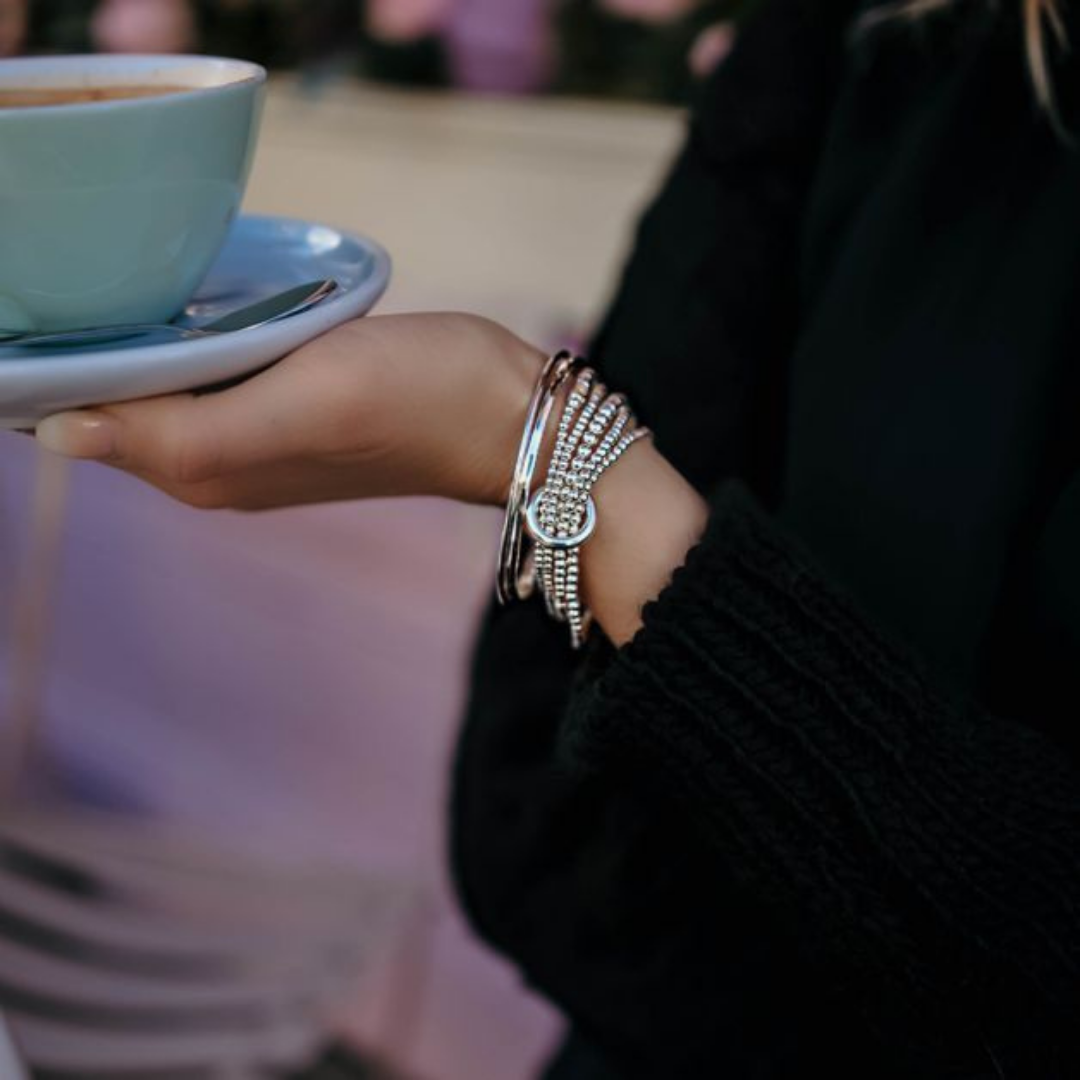 Model wearing annie haak yard of silver bracelet holding cup