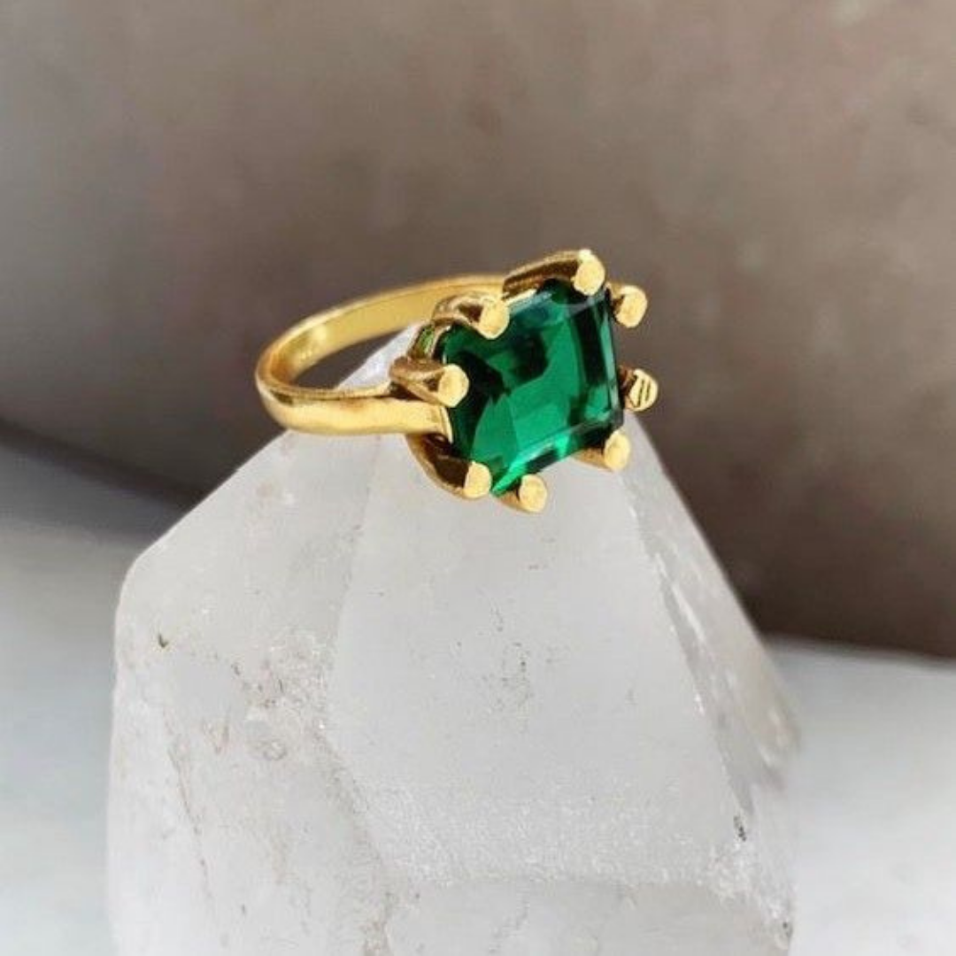 Green and gold ring by shyla london displayed on top of a large crystal