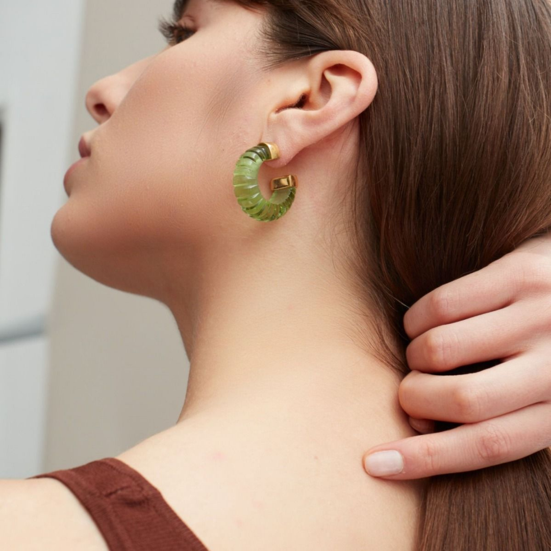 Photograph of a woman from behind, she is wearing a hoop earring made from green glass