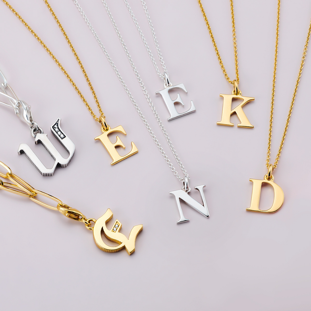 Photograph of some charms in the form of letters. They are on necklaces and spell out the word 'weekend'