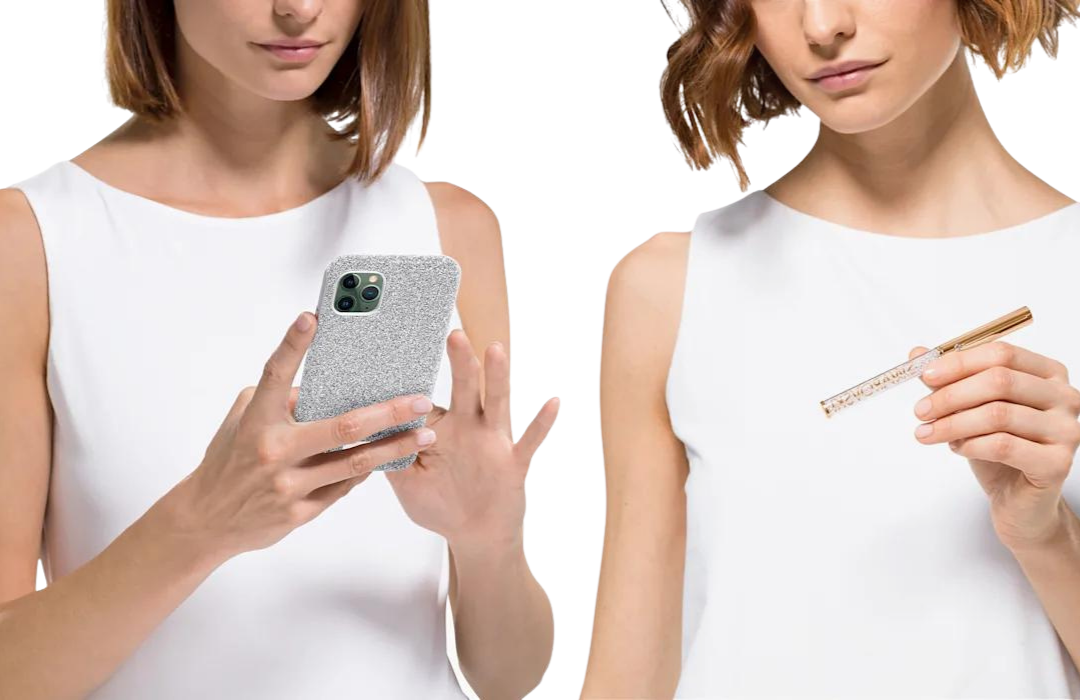 photograph of two women. One is holding a phone in a silver case by Swarovski and the other is holding a gold pen made by swarovski