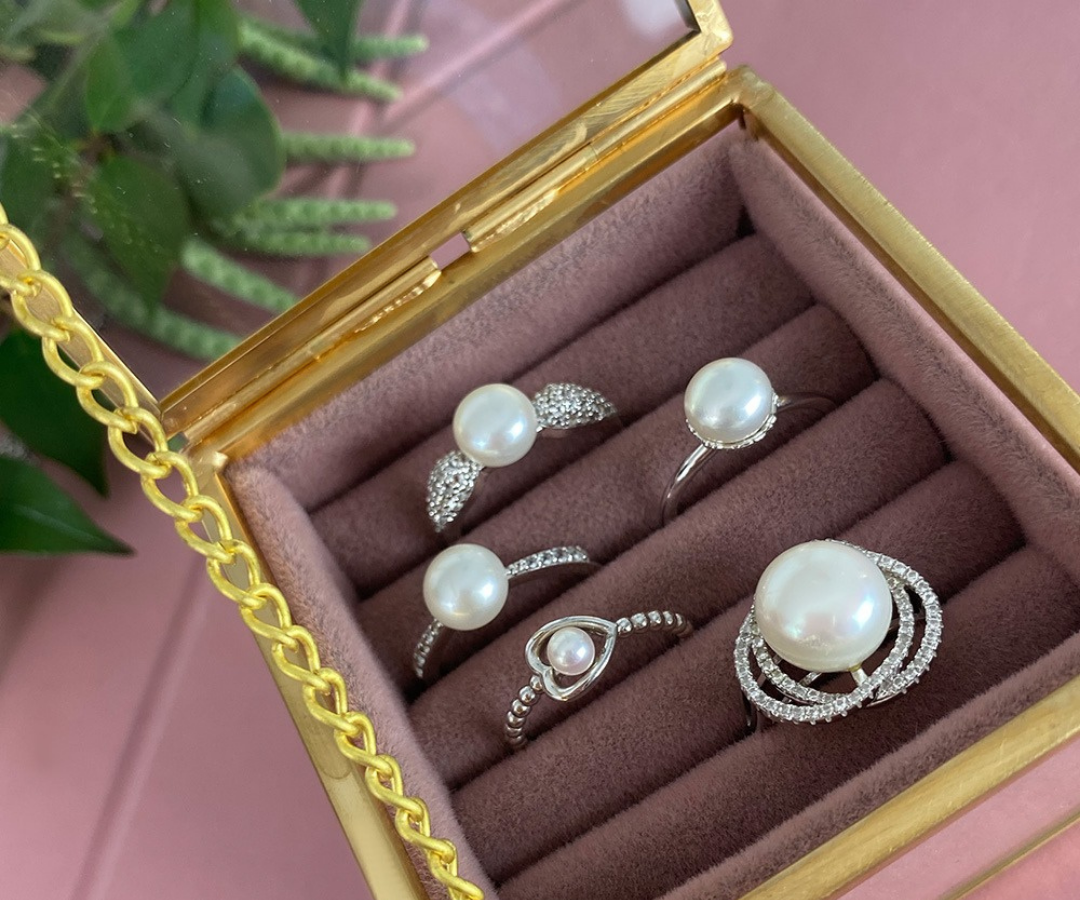 Photograph of several pearl rings in a jewellery box